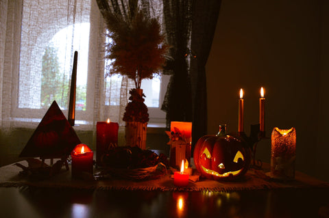 a table topped with candles and pumpkins next to a window