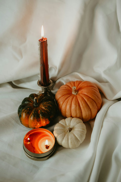 a candle and some pumpkins on a white sheet