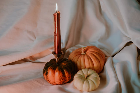 a candle and some pumpkins on a white cloth