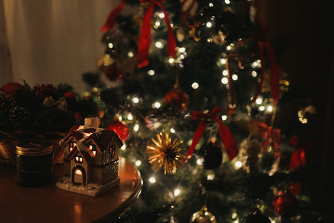 A lit christmas tree with a red ribbon around it