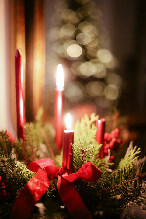 Red candles glow on a festive christmas wreath.