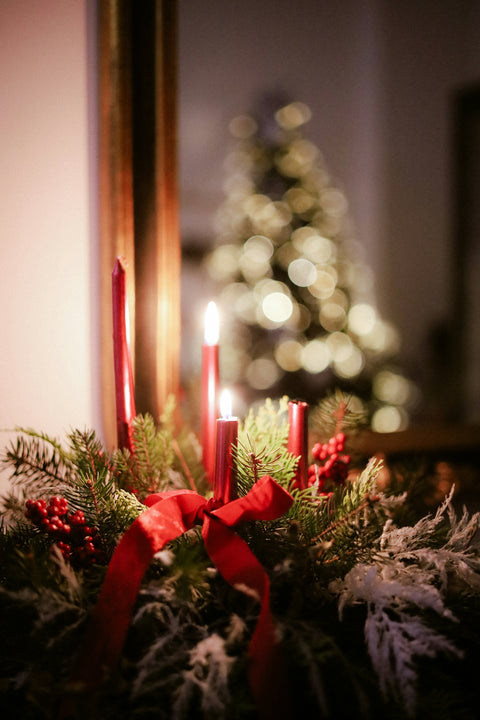 Advent wreath with lit candles and christmas tree reflection